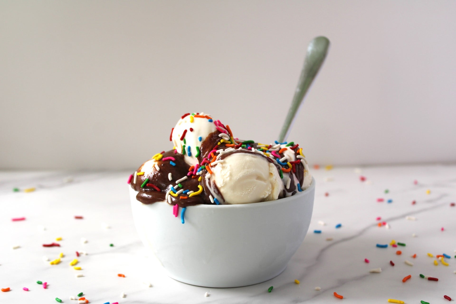 hot fudge sauce in a bowl with ice cream and sprinkles.