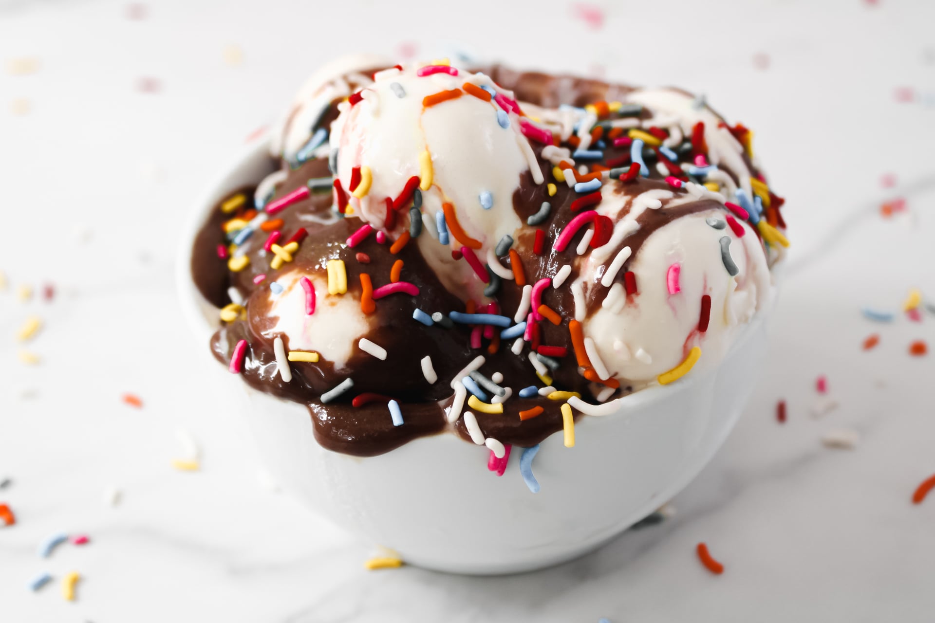 Hot fudge sauce with ice cream and sprinkles in a bowl