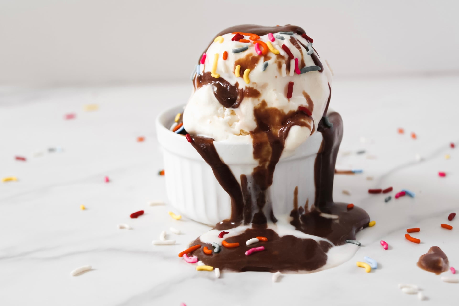 Hot fudge sauce with ice cream and sprinkles in a bowl.