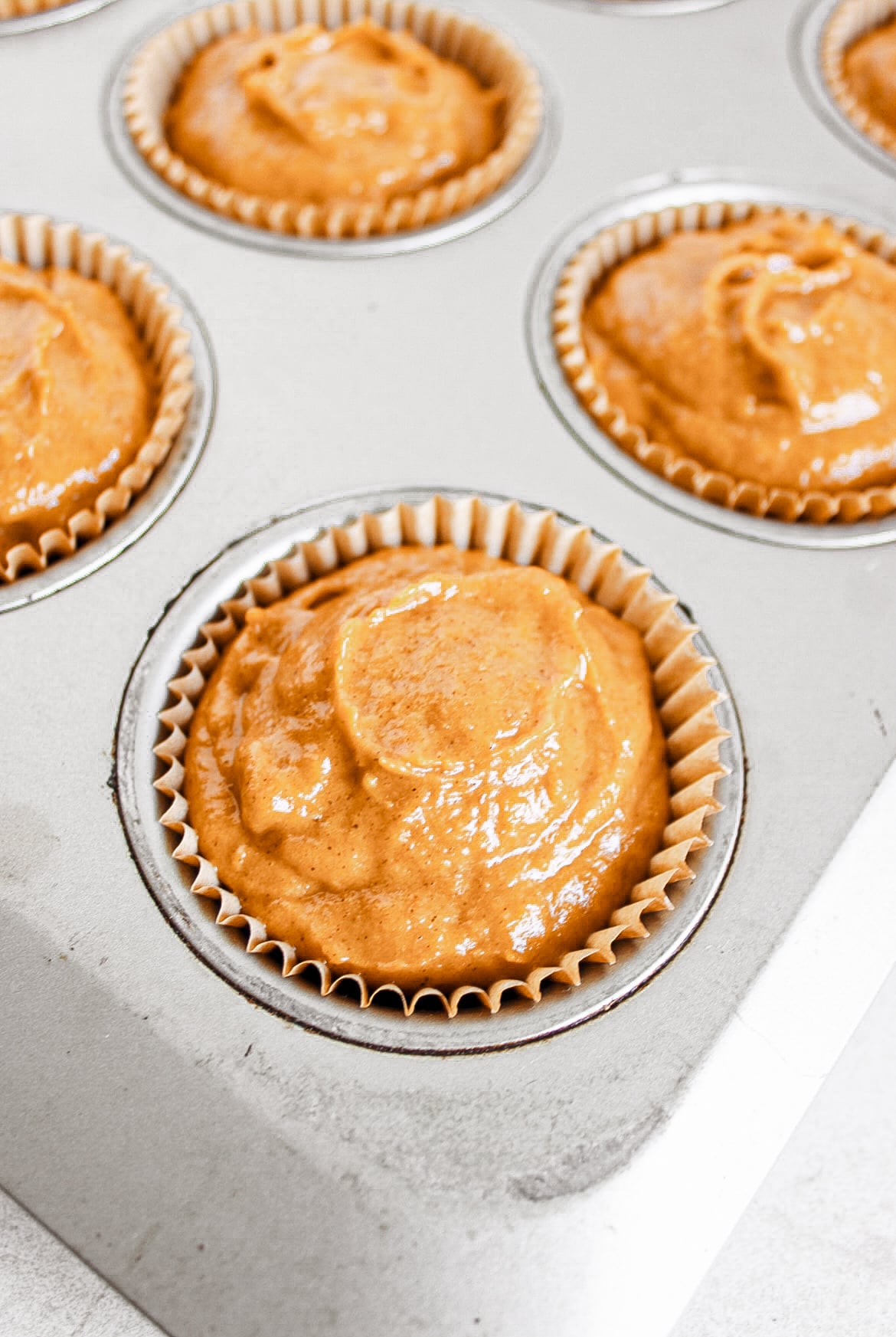 Pumpkin batter in a cupcake liner ready to bake