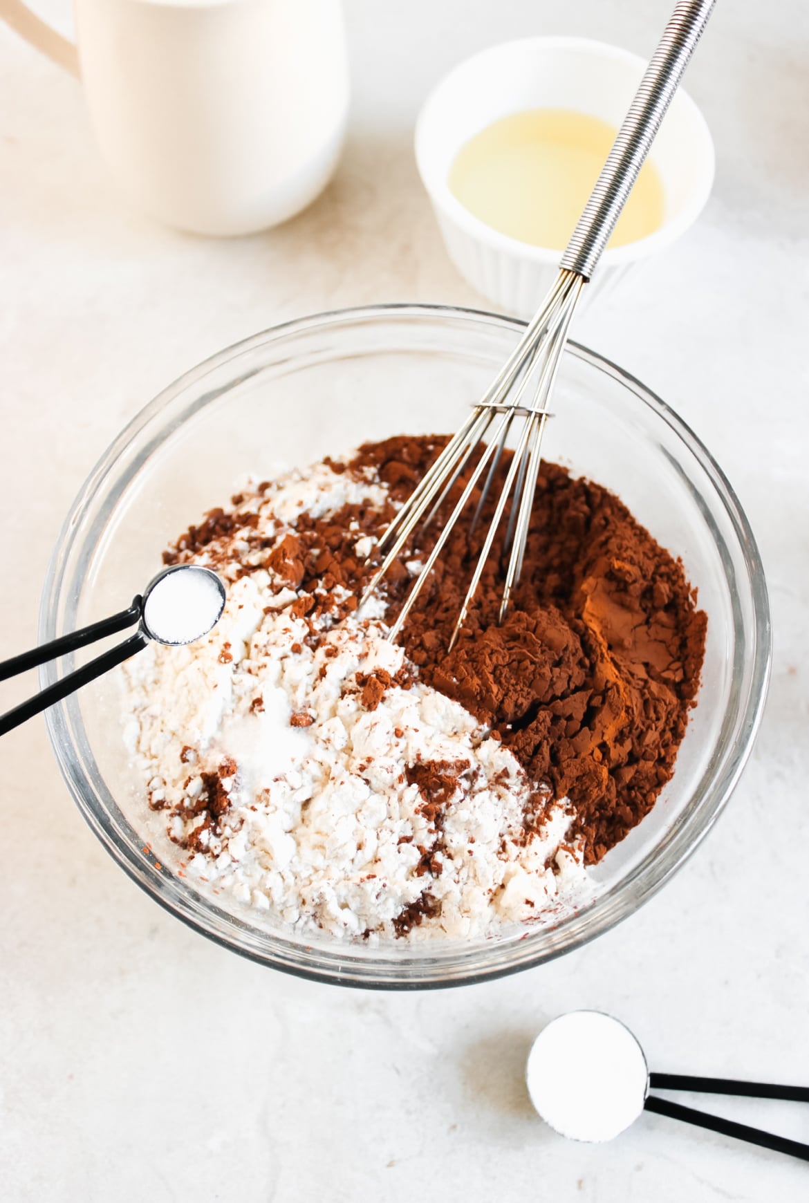 Flour, sugar, cocoa, baking soda, and salt in a bowl. With a whisk and measuring spoons.