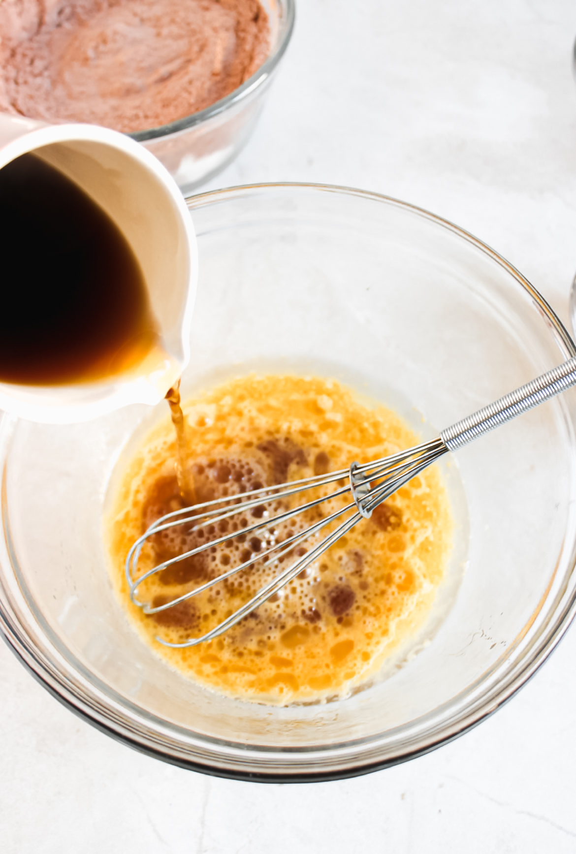 Butter, coffee, oil, and eggs in a bowl with a whisk.