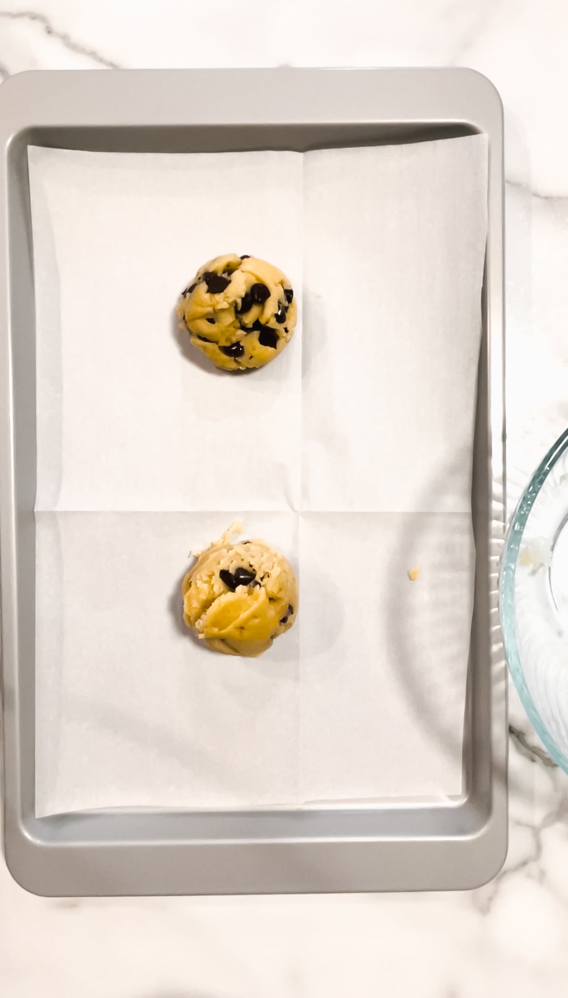 Cookie dough on a sheet pan with parchment paper and mixing bowl.