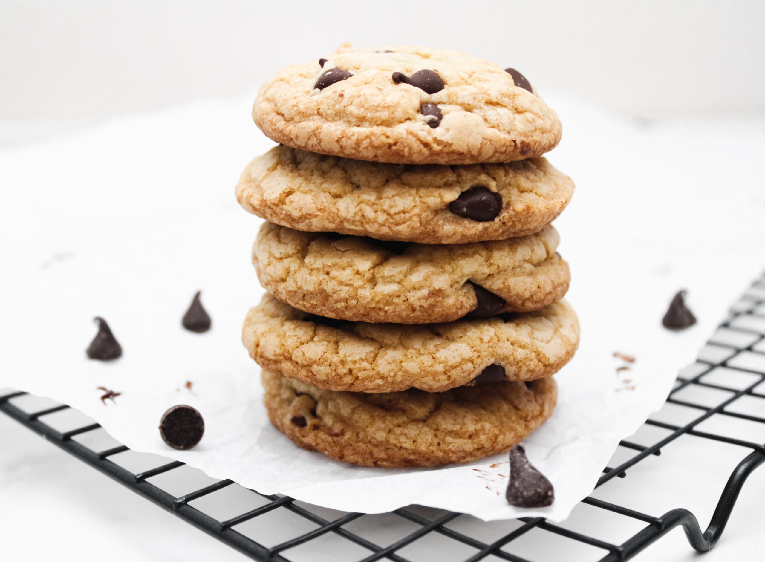 Fully baked chocolate chip cookies on a cooling rack.