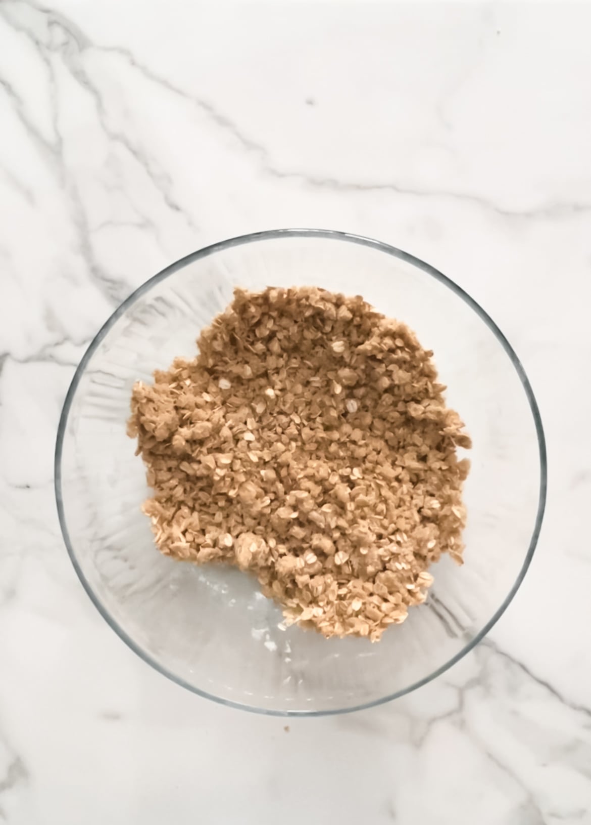 The crumble base of the raspberry oat bars in a glass mixing bowl.