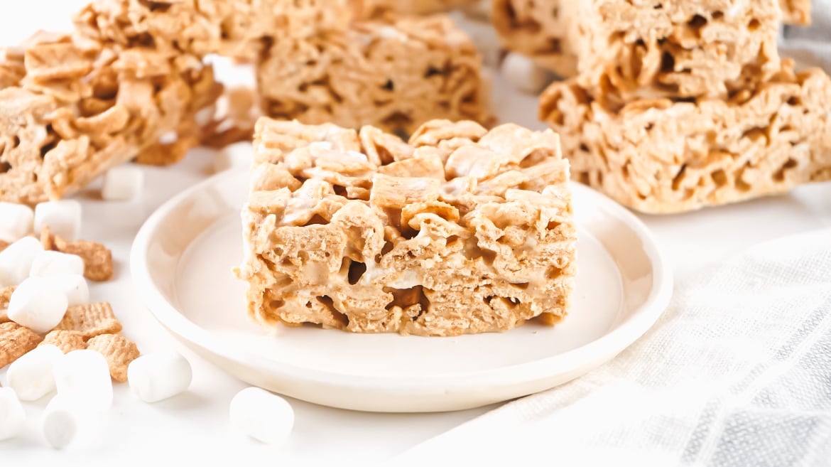Tasty brown butter cinnamon toast crunch rice krispy treats bars on a plate with marshmallows. 