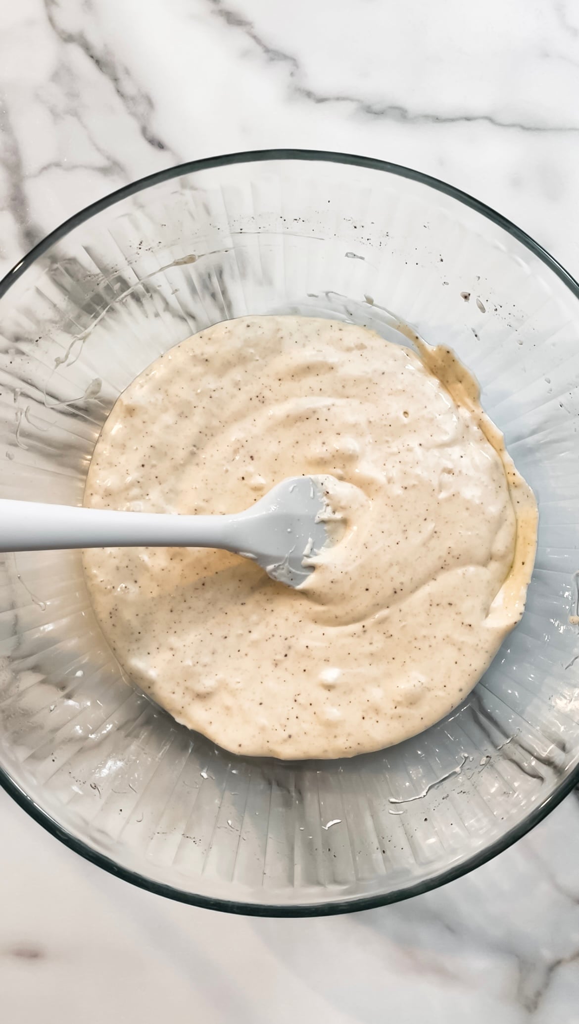 Melted marshmallows, and butter in a glass bowl with a spatula.