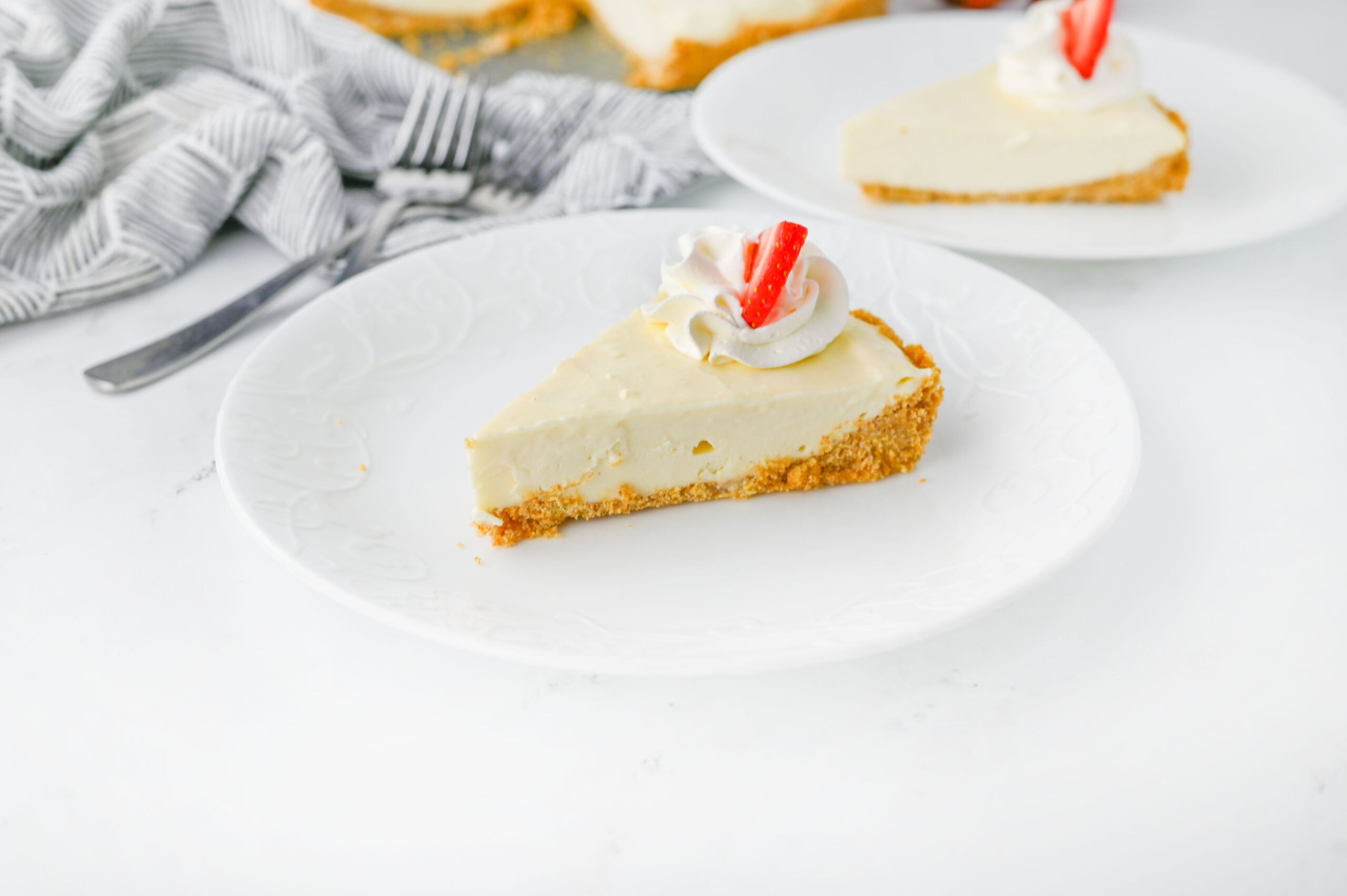 Fully prepared no-bake cheesecake on a plate with forks and a napkin.