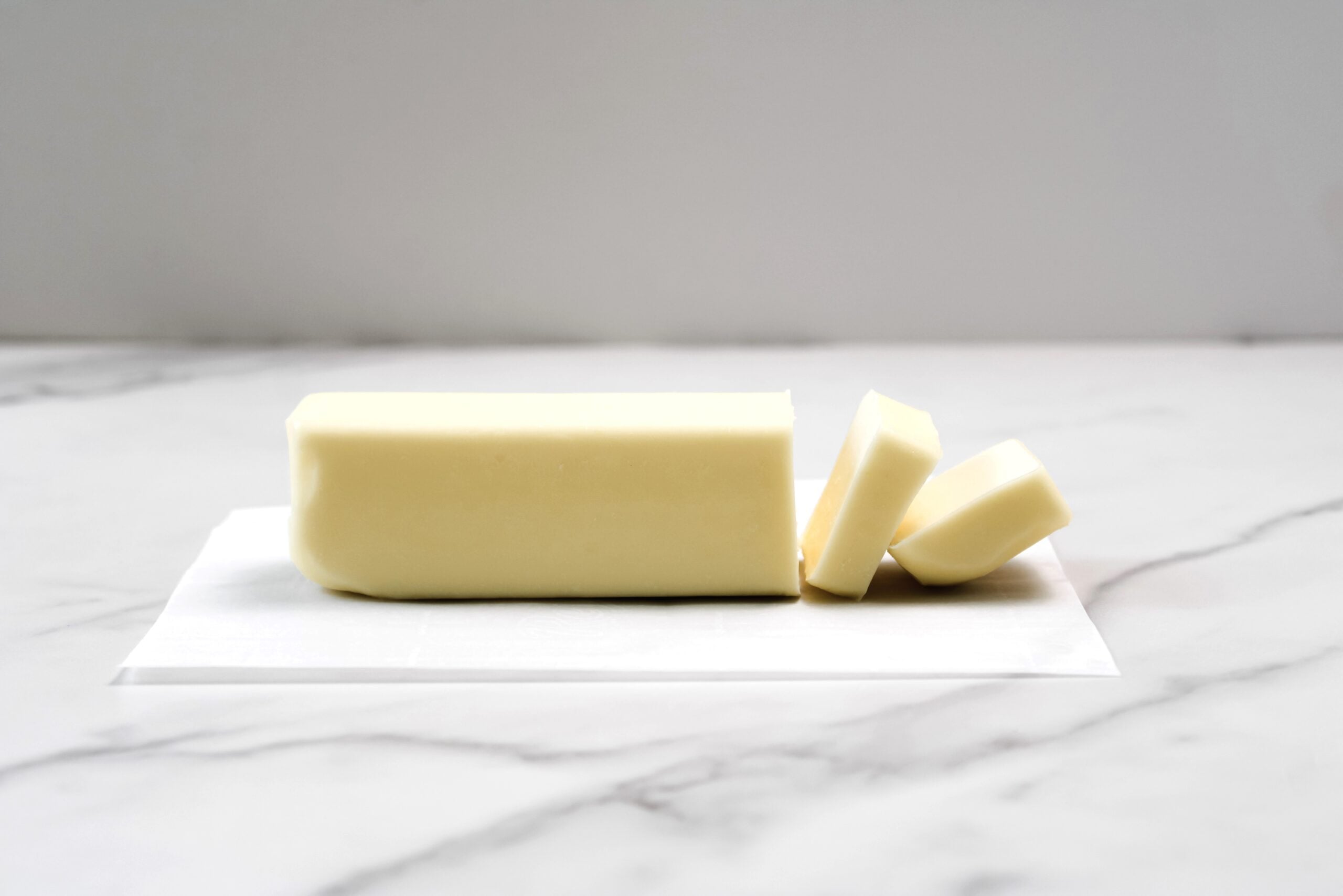 Stick of butter sliced on parchment paper. 